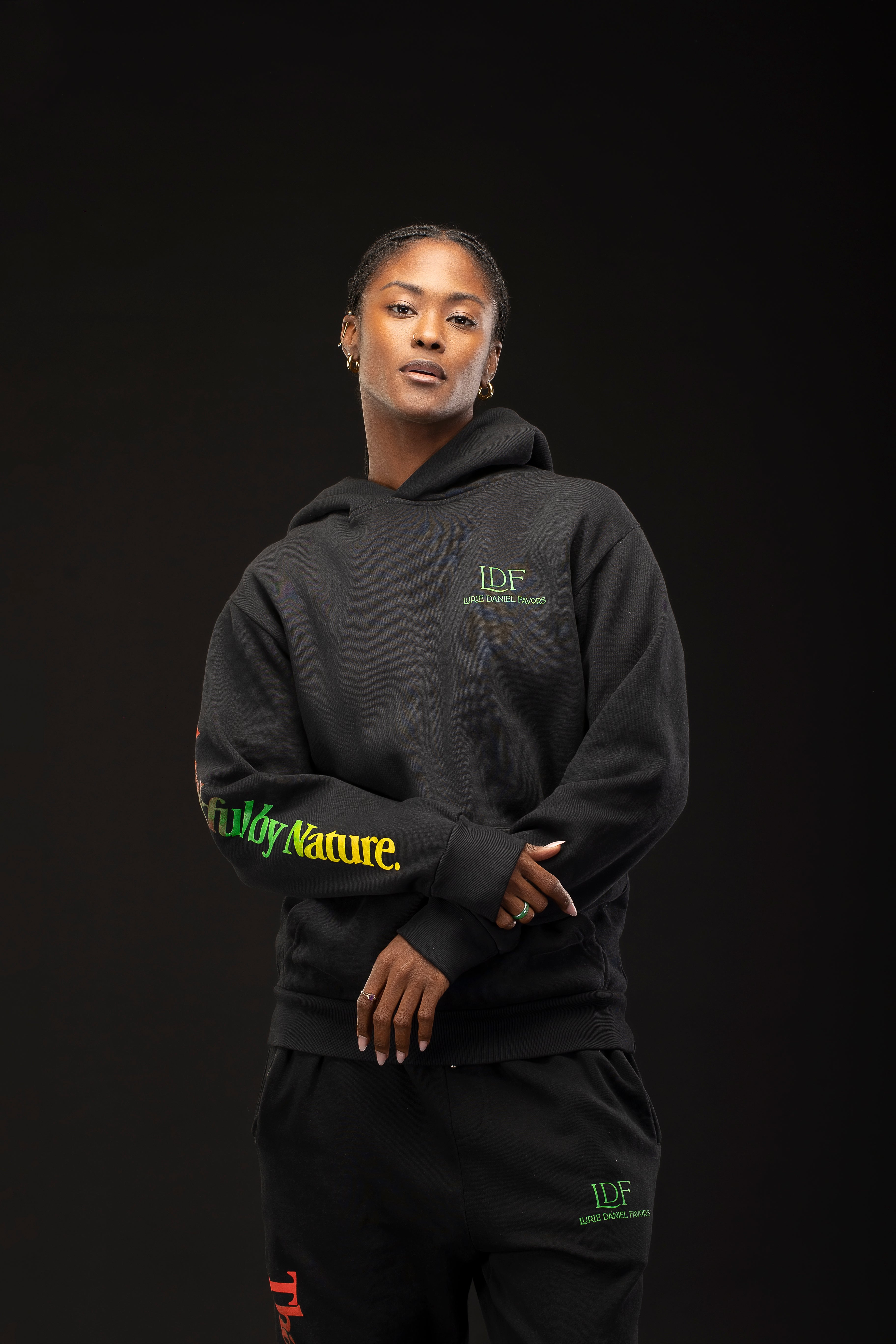 Woman wearing a black hoodie with visible branding on a dark background