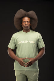 Person wearing a green t-shirt with 'Thankful by Nature' text on a black background
