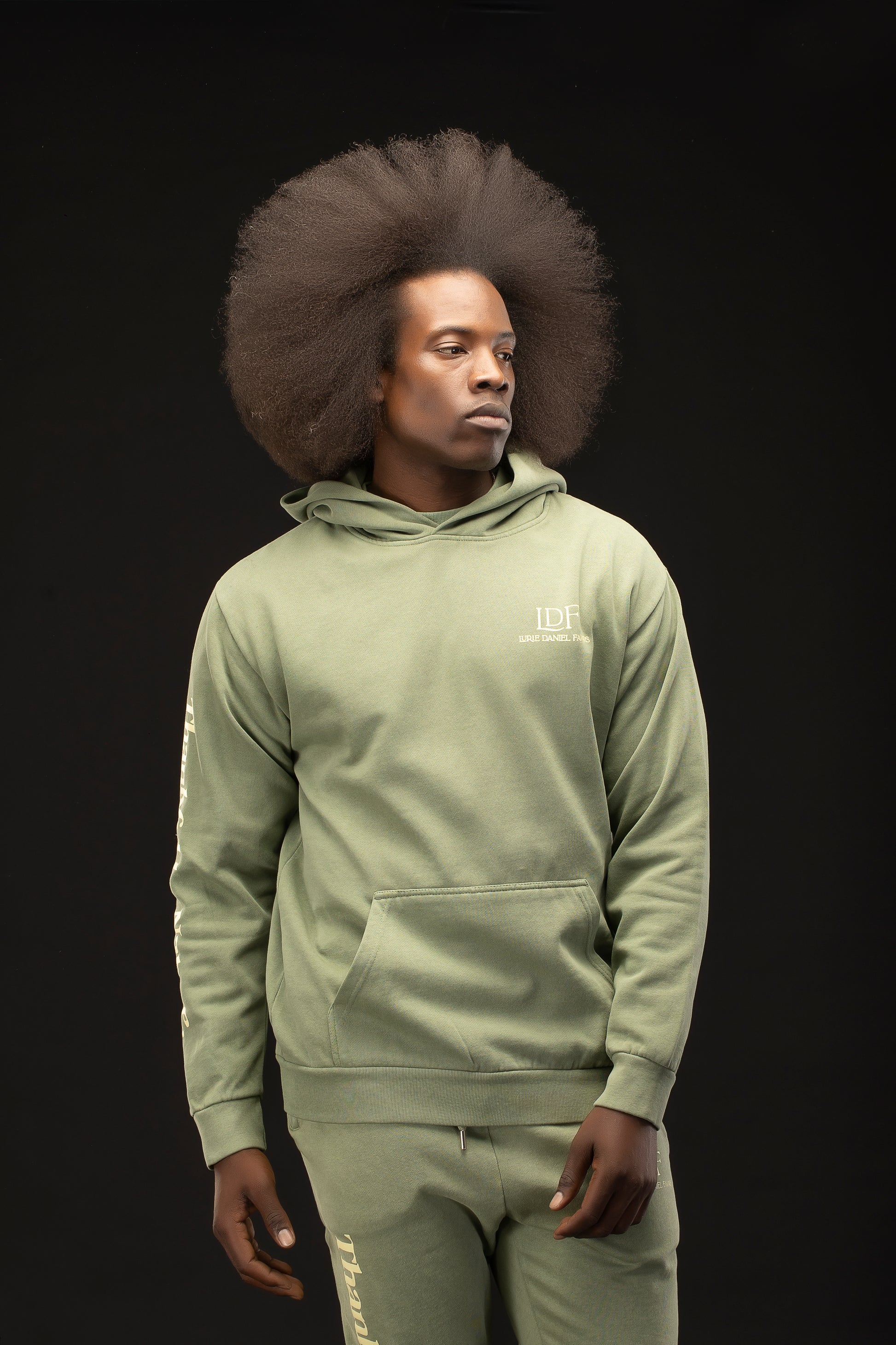 Man wearing a green hoodie and pants with a black background