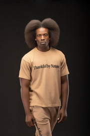 Man wearing a beige t-shirt with 'Thankful by Nature' text on a black background