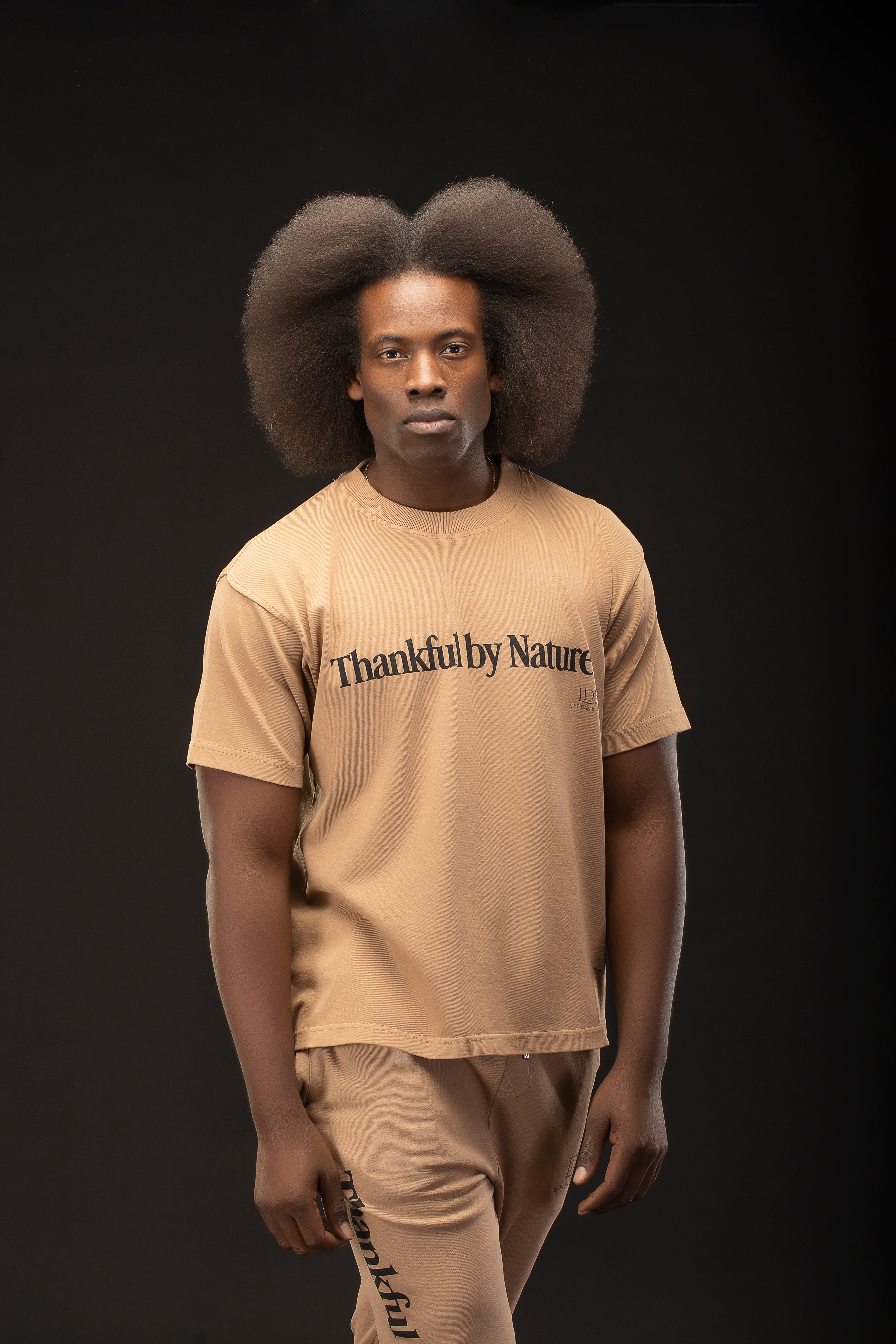 Man wearing a beige t-shirt with 'Thankful by Nature' text on a black background