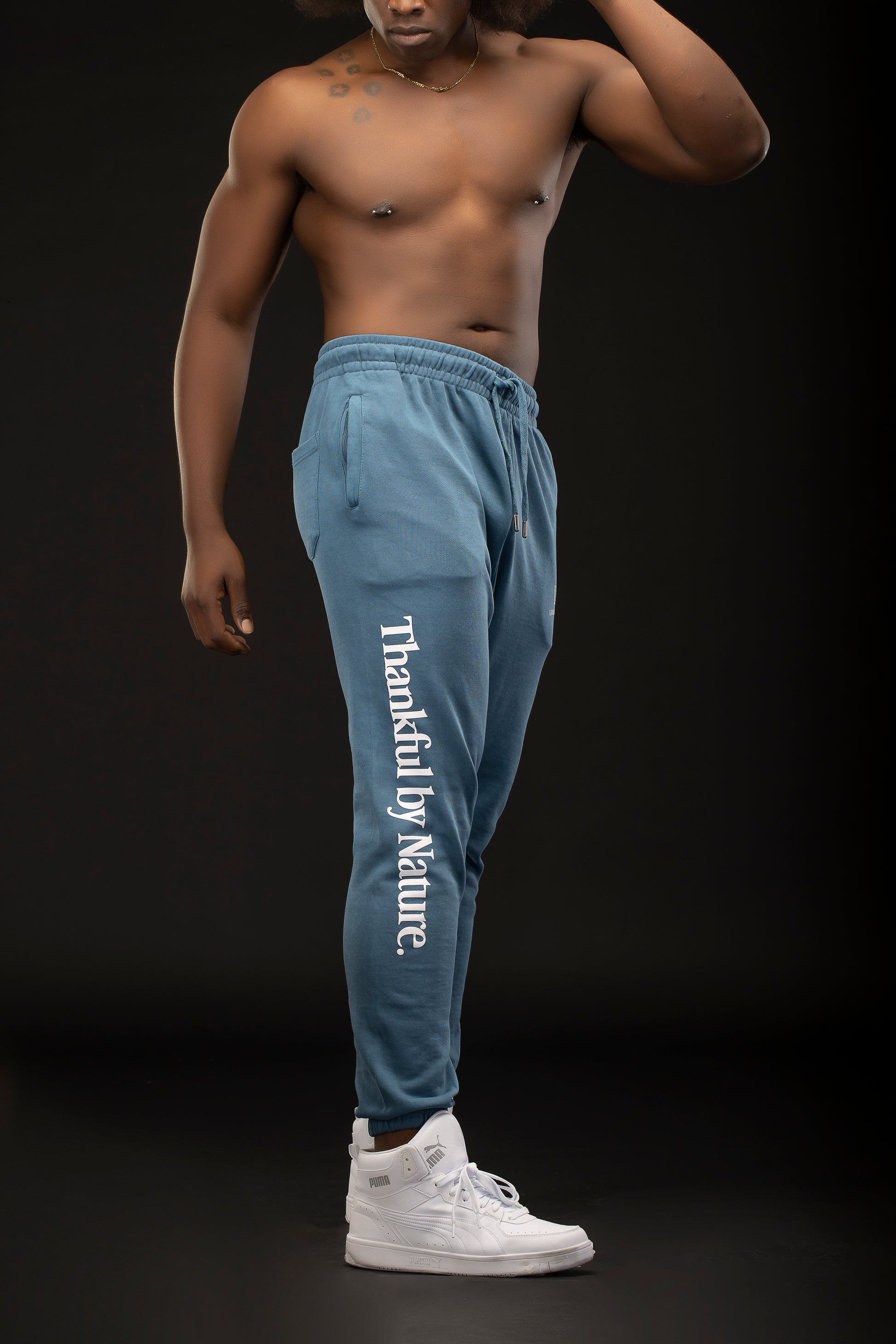 Man wearing blue sweatpants with 'Thankful by Nature' text on a black background